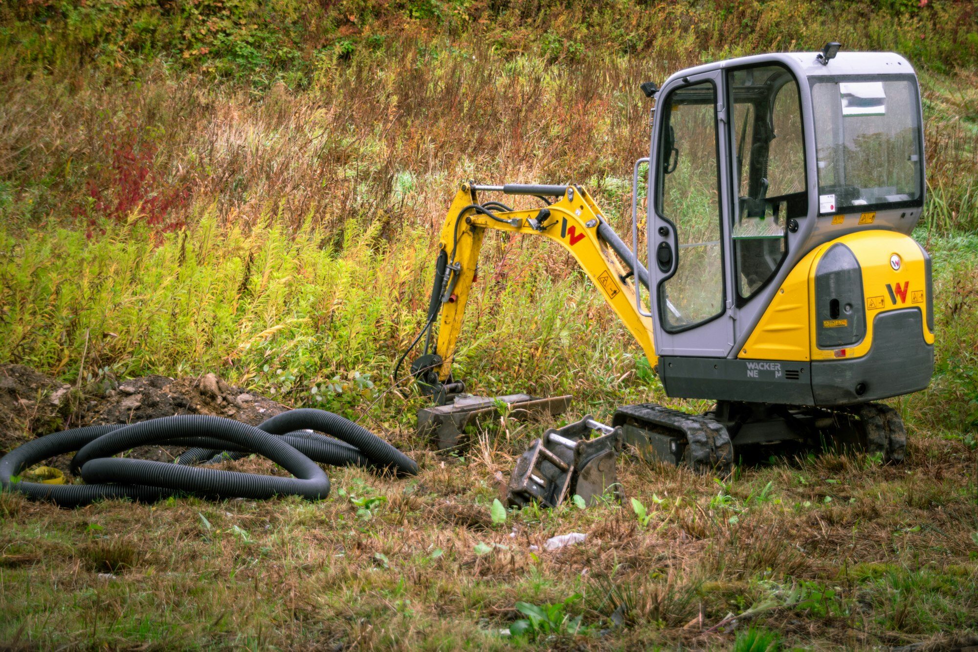 Offener Graben mit Drainagerohren neben dem Bagger